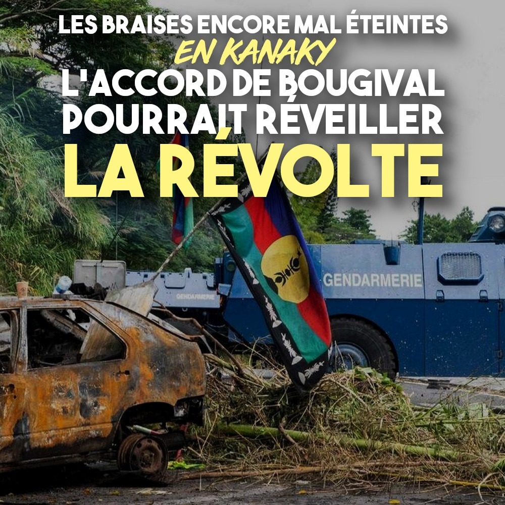 Un drapeau de la Kanaky flotte au-dessus d'une carcasse de voiture brûlée devant un blindé de la gendarmerie française.